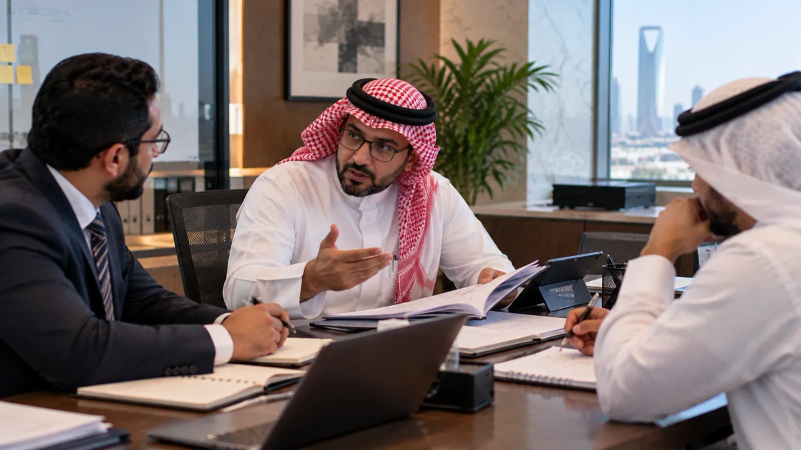 A consultant talking an open personnel file through with two colleagues taking notes at a meeting